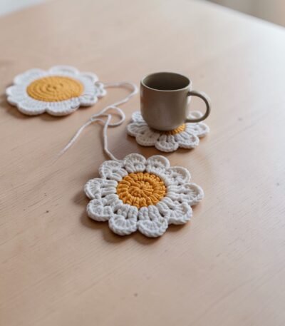 Handmade crochet daisy flower coaster made with chunky yarn placed under a coffee mug