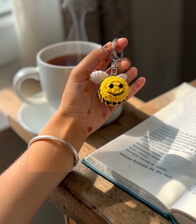 handmade crochet smiling bee keychain with wings held in hand