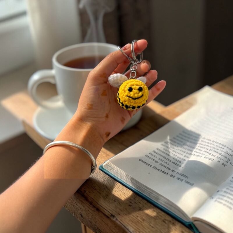 handmade crochet smiling bee keychain with wings held in hand