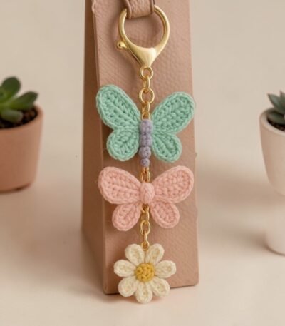 handmade crochet butterfly and daisy keychain hanging on bag