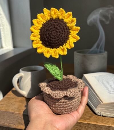 Handmade crochet sunflower flower in a small decorative pot placed on a wooden table