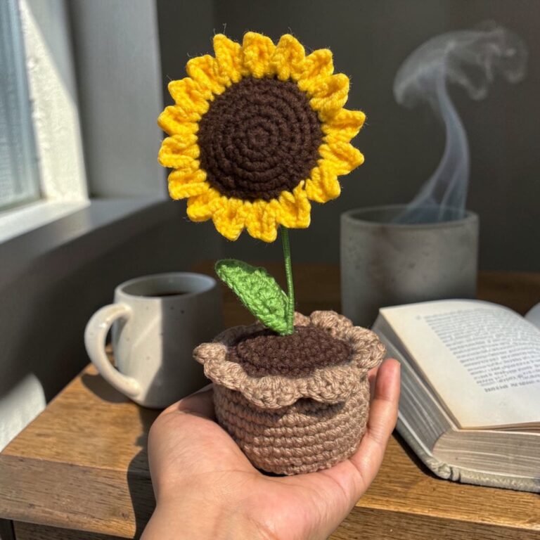 Handmade crochet sunflower flower in a small decorative pot placed on a wooden table