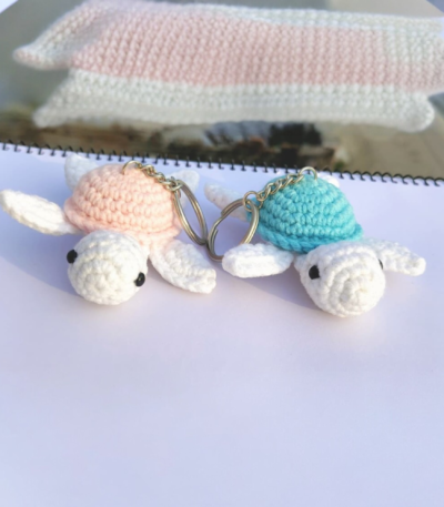 Two handmade crochet turtle keychains in pastel colors placed on a white surface